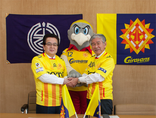 美浦町長とギラヴァンツ北九州の横手社長、マスコットキャラクターのギランが握手